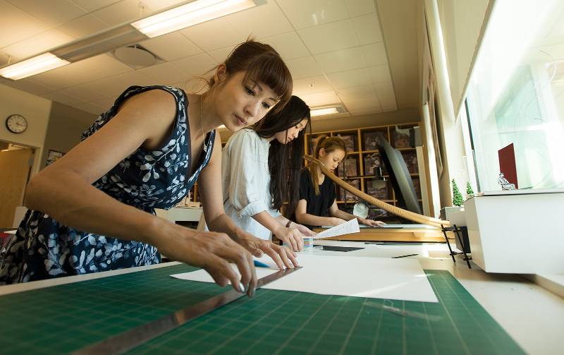 A professor works with interior design students in a lab.