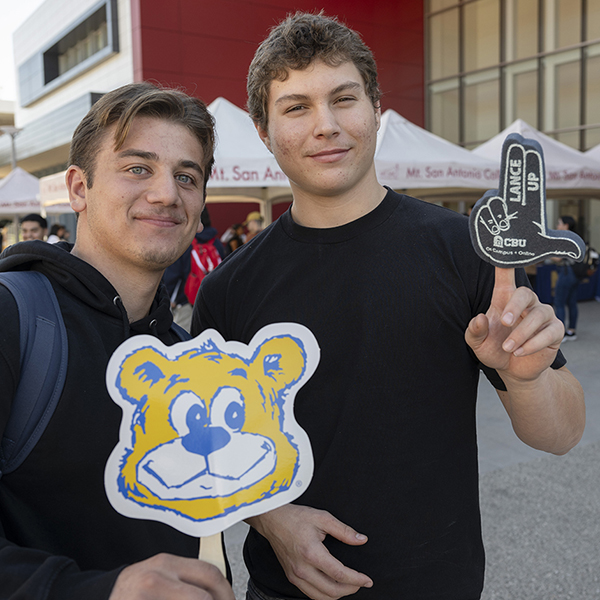 Students hold up transfer college information at an event.