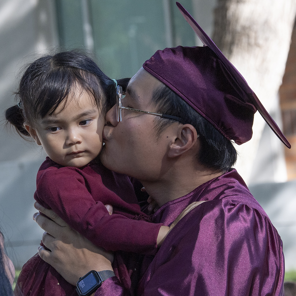 A Mt. SAC graduate kisses his young child at graduation.