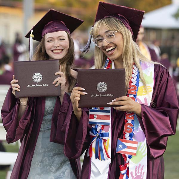 Two Mt. SAC graduates hold up diplomas at commencement in 2026.