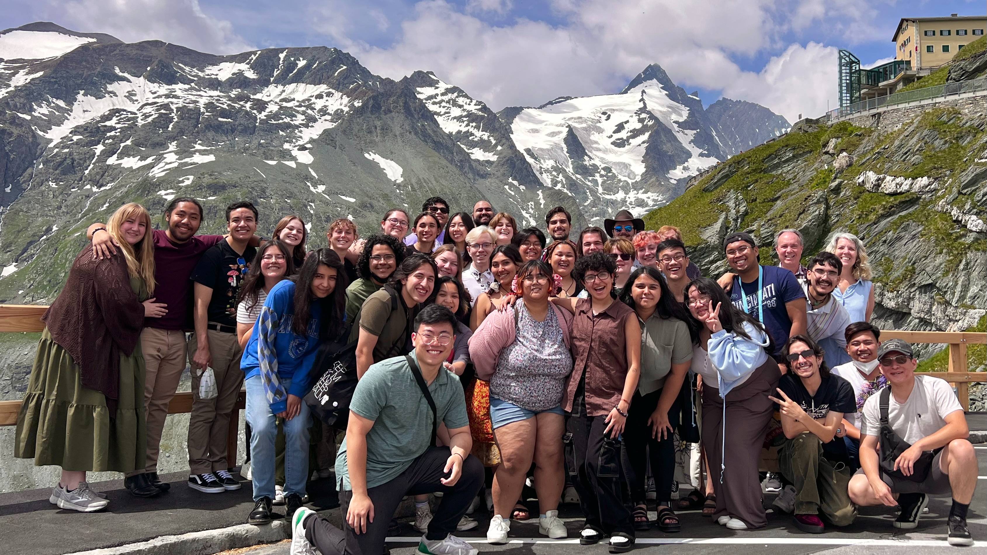 Group of people gathered for photo in front of picturesque mountains.