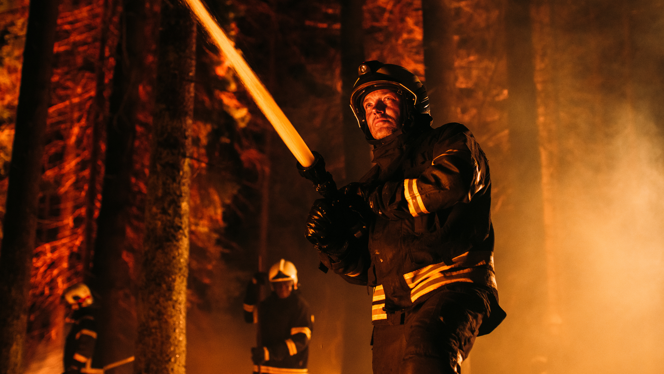 Male firefighter sprays water on fire