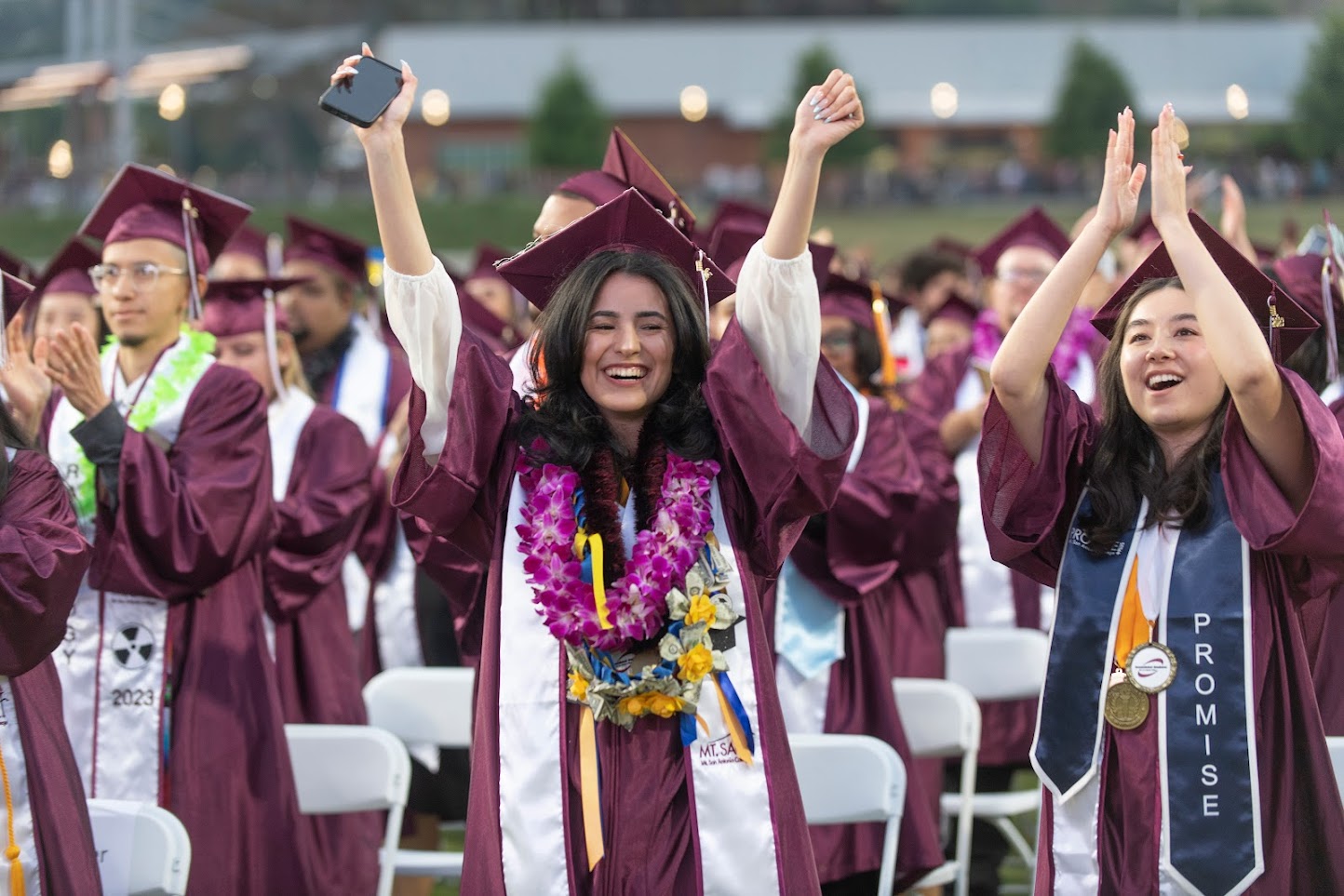 Female smiling and holding up her arms at graduation