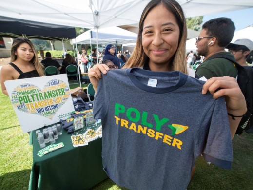 Female student holding a dark blue tshirt with the words Poly Transfer printed on it in yellow and green.