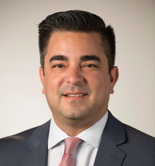 Robert Hidalgo in a traditional portrait of a Latino male dressed in a dark suit