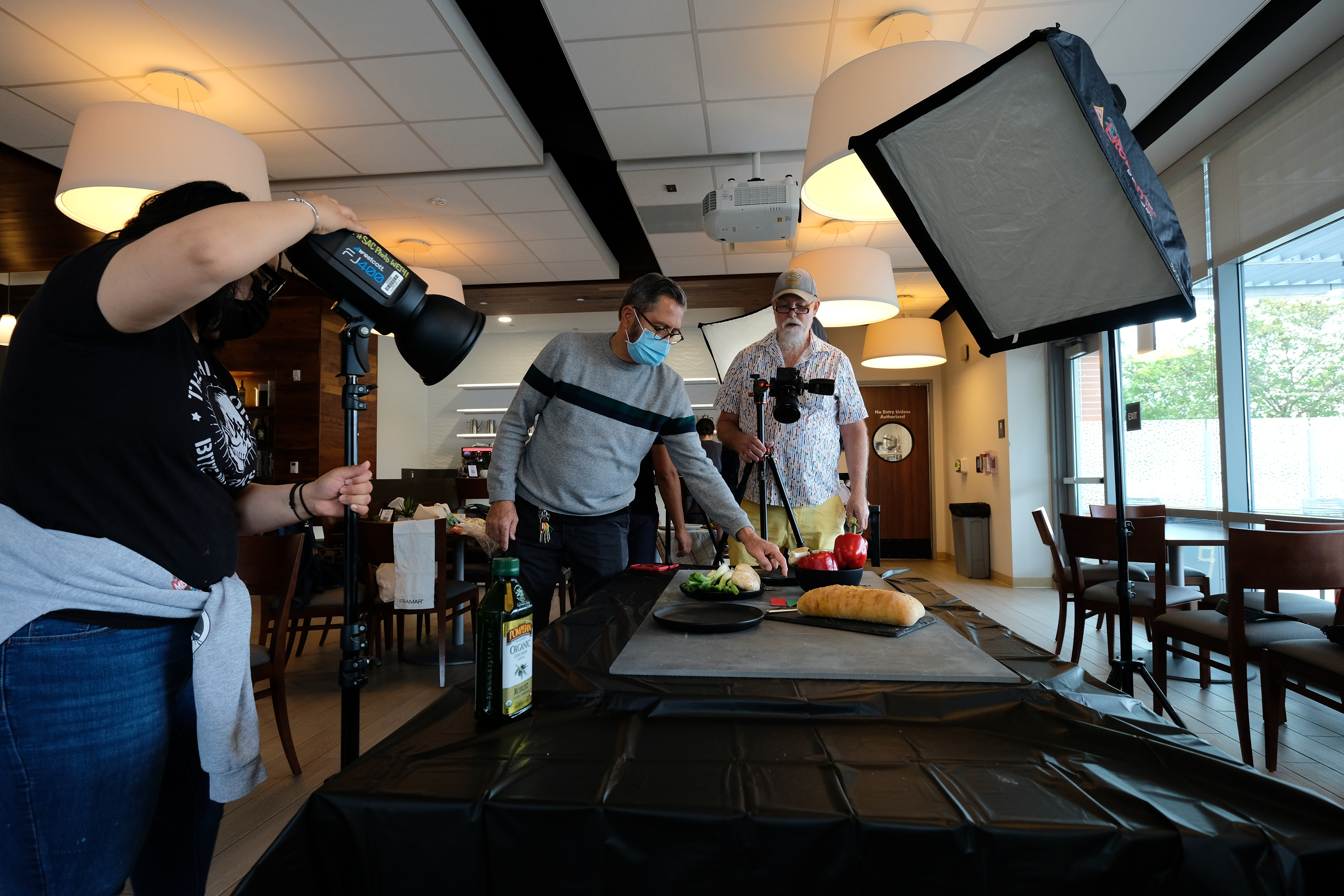Instructor works with two students on a food still life photoshoot in Cafe 91