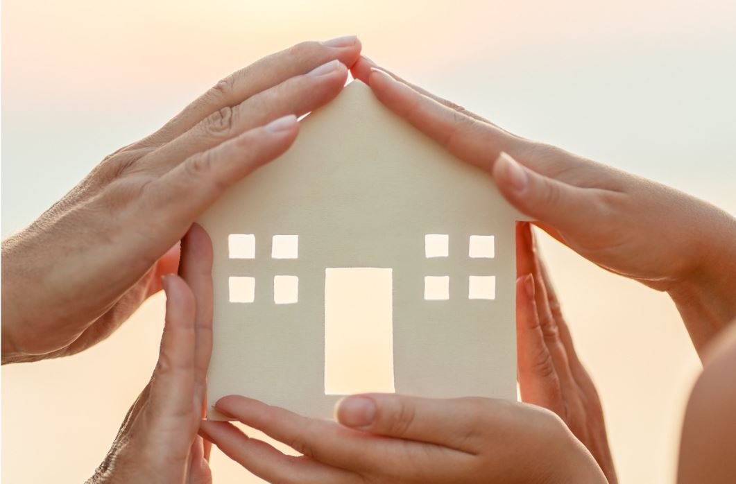 house cut out with hands around it